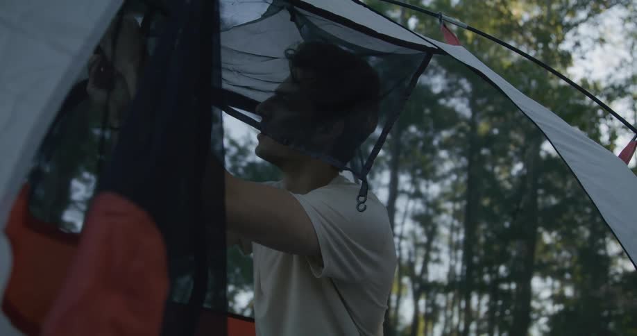 A man is in the woods and setting up a tent