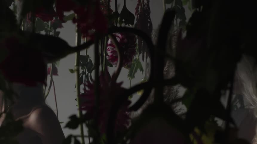 Two women walking through hanging flower arrangements