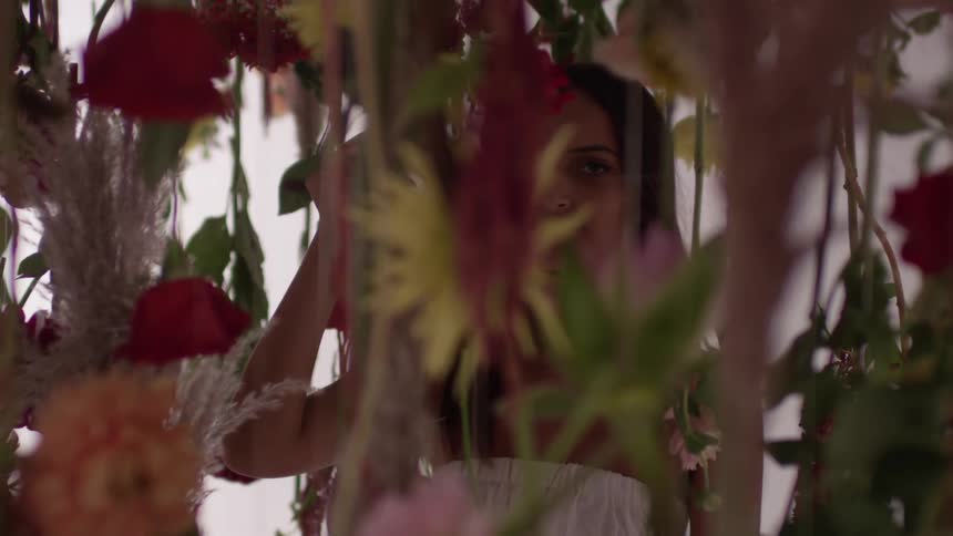 A woman is standing among vines and flowers