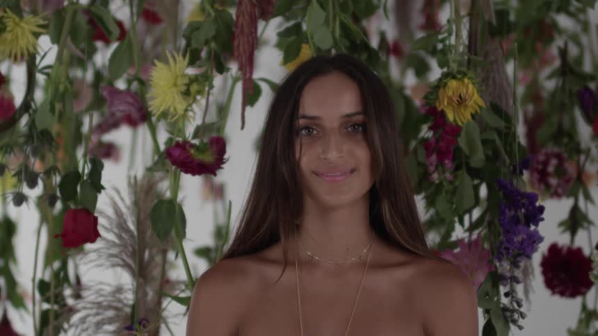 White-gowned woman standing amongst hanging flowers