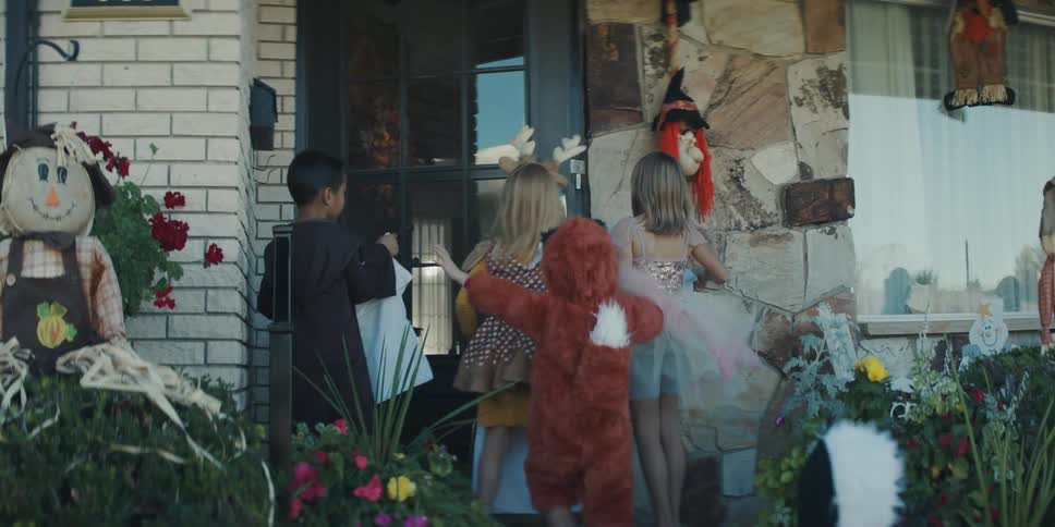 Group of kids on costumes asking for trick or treat on the house of a neighbour