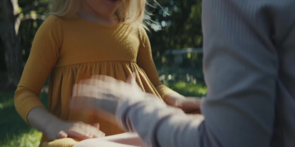 Two little girls sitting on the lawn playing patty cakes