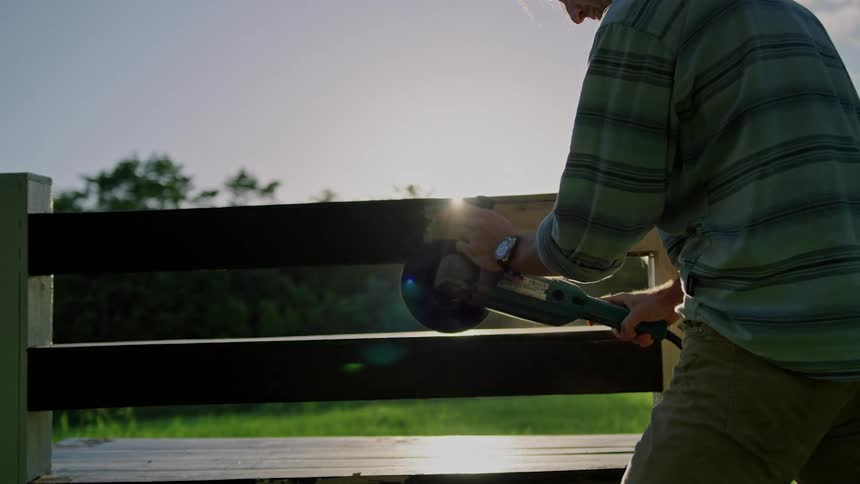 A man working on a piece of wood for a fence