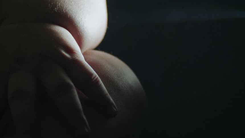 Sun shines onto pudgy child sitting in dark area