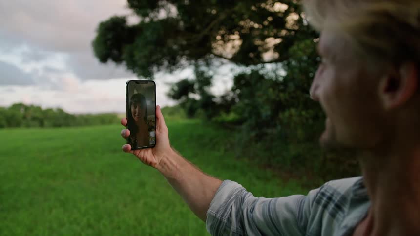 A man is video chatting with his wife outdoors in spring