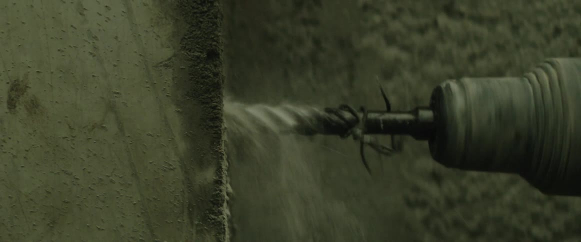 A power drill drilling into cement causing dust