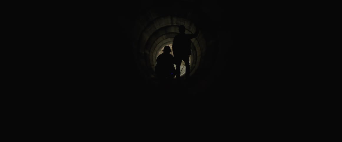A view of two soldiers shining a laser down a tunnel