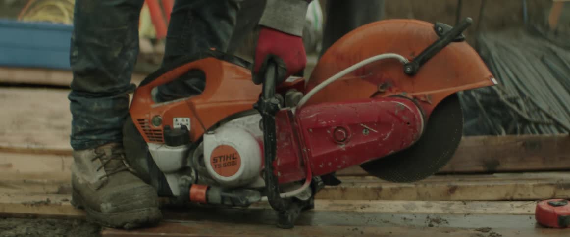 A construction worker starts his cut off saw with one pull