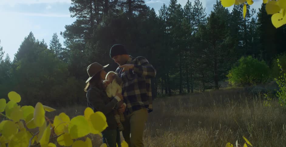 Mom kisses baby as dad brings his finger from way up high down to babys face