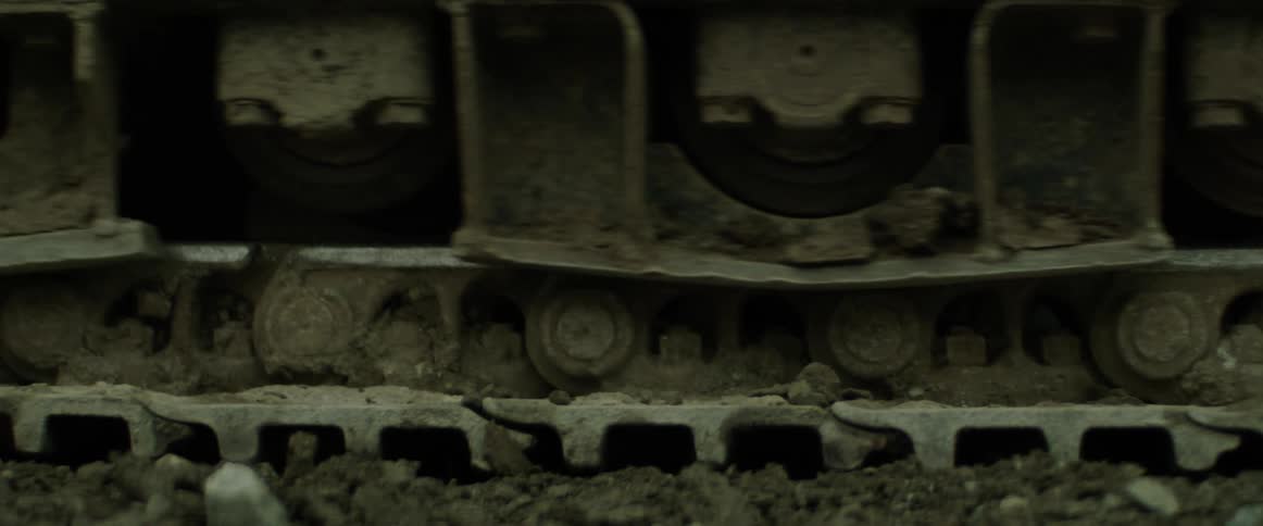 A piece of construction equipment moves on a continuous track tread in dirt