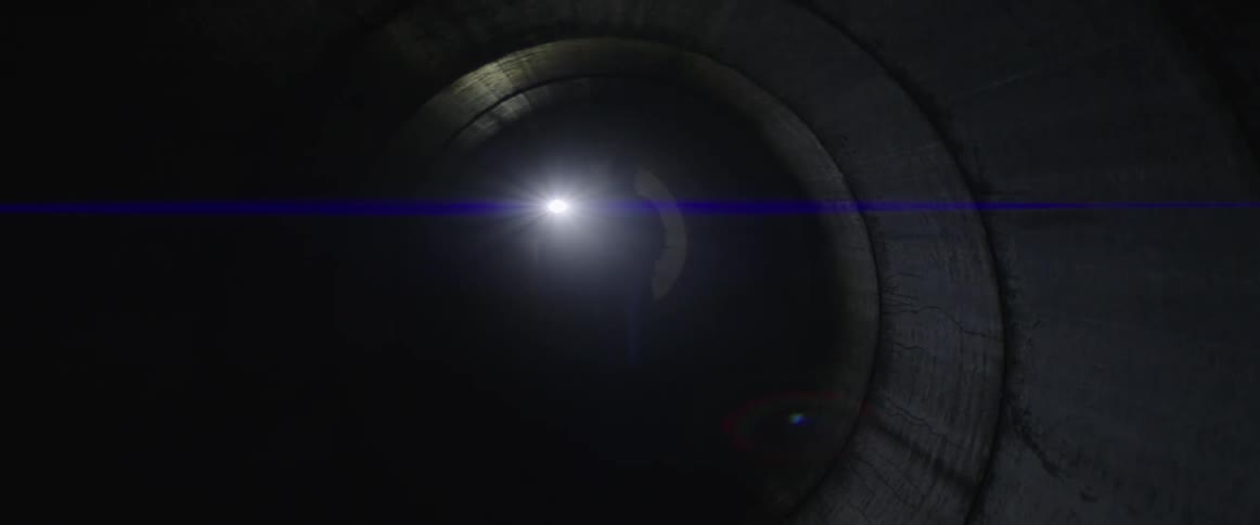 A person shining a flashlight inside a pitch black tunnel