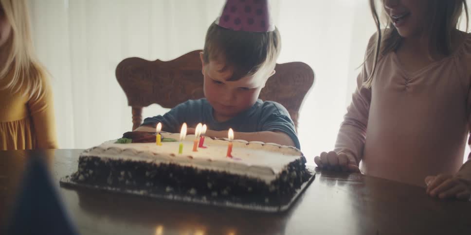 Mother brings a cake the table for the birthday boy to the candles