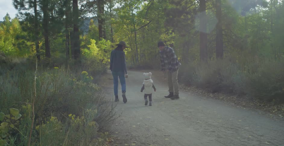 Baby walking on trailhead in the forest with father and mother
