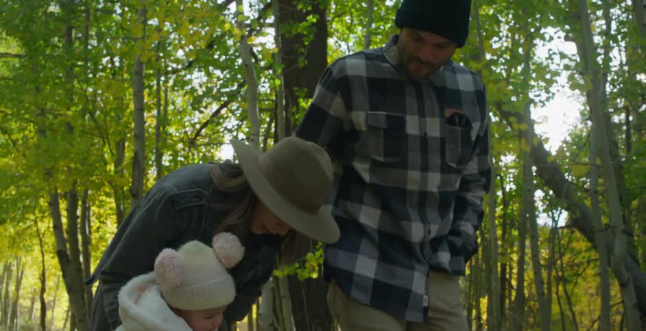 A young family with a baby walking in a forest on a sunny autumn day