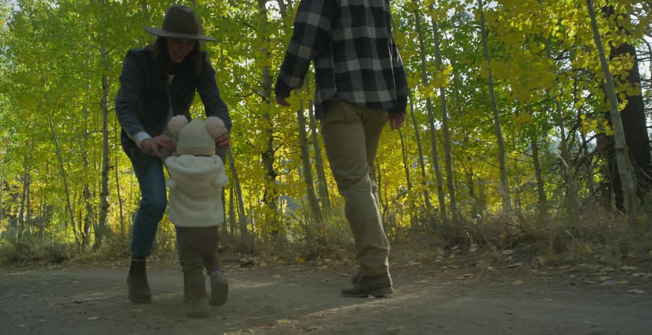 Mom holds her arms out walking backwards encouraging her daughter to walk to her then lifts her up