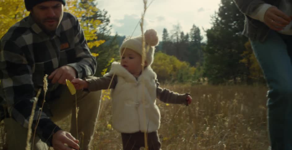 Parents and their child look at the grass together