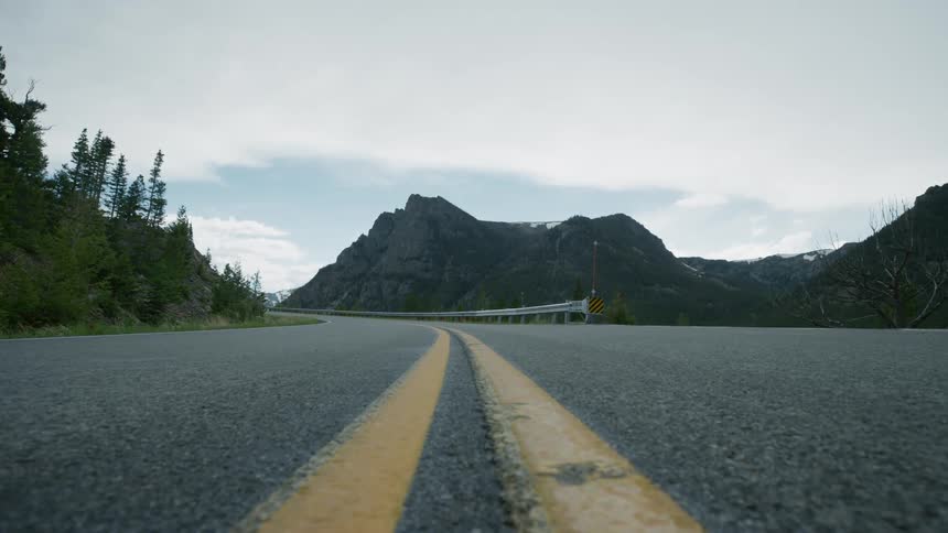 Close up of the double yellow line in the middle of a road in the mountains