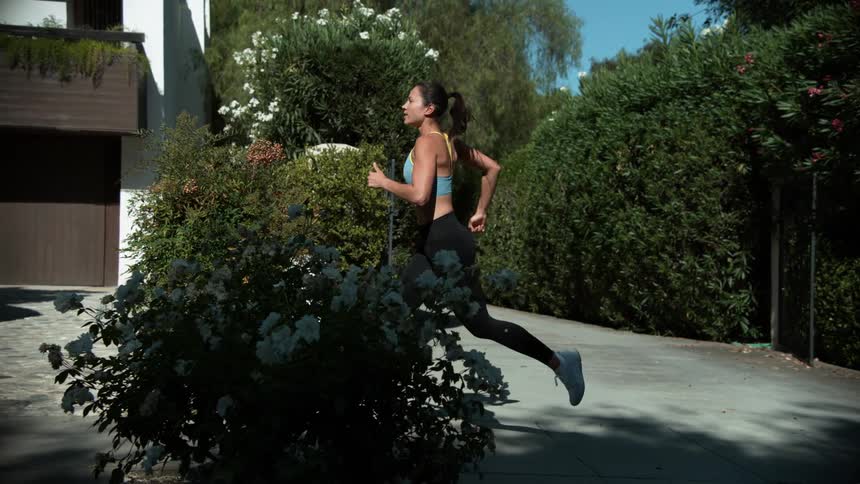 Woman runs past building with parked car nearby