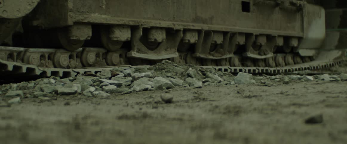A piece of equipment moving on a continuous track tread over dirt