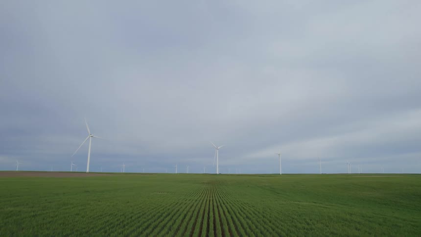 Wind turbines are spinning on a wind farm in a farm of crops