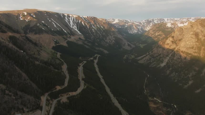 Dirt paths wind through the valley of a snow capped mountain range