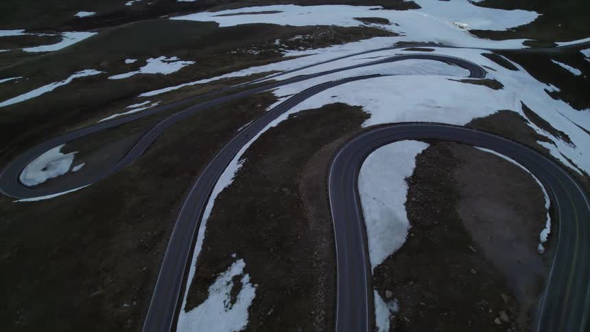 Aerial view of person riding bike on winding road on snowy hill