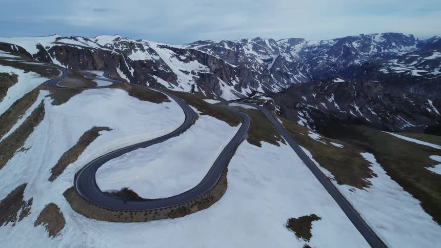 Cars are driving on a road over the mountains in winter