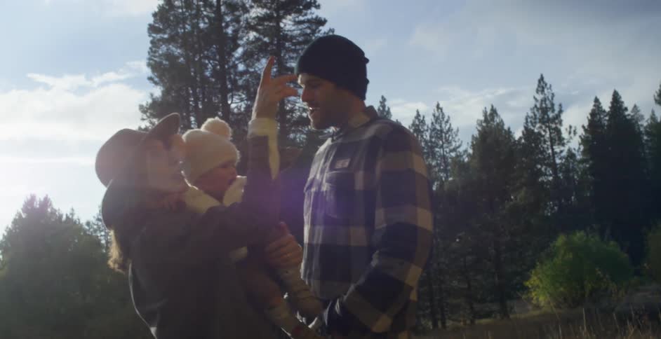 A family is outdoors in a wooded area at dusk