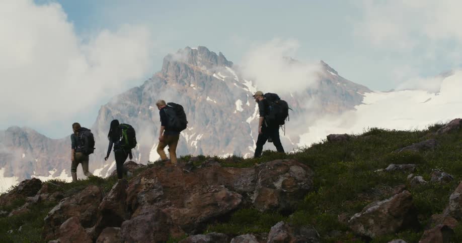 A group of people hike across a mountain ridge during the day