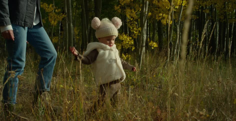 Toddler walking with her mother on a clearing in the forest tumbles and falls on the ground