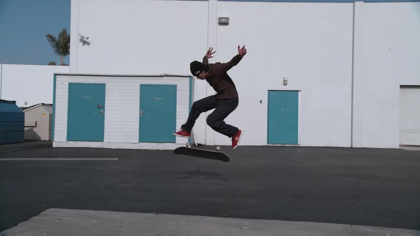A male is skateboarding in an empty parking lot