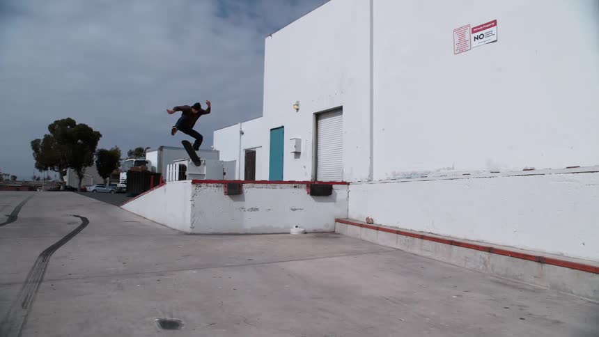 A man is skateboarding in an empty parking lot
