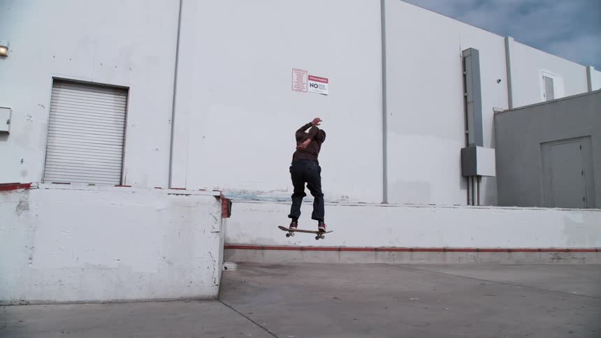 A man is skateboarding in an empty parking lot