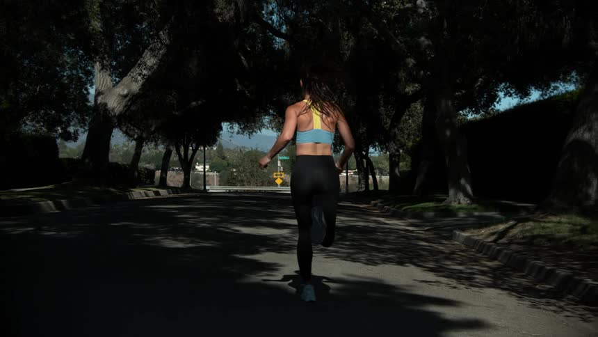 A woman is jogging on a street in spring