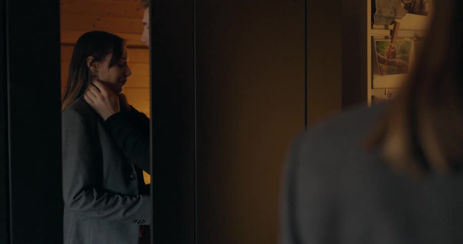 Woman standing in front of a mirror at home receives a kiss in the forehead from her partner after trying a blazer