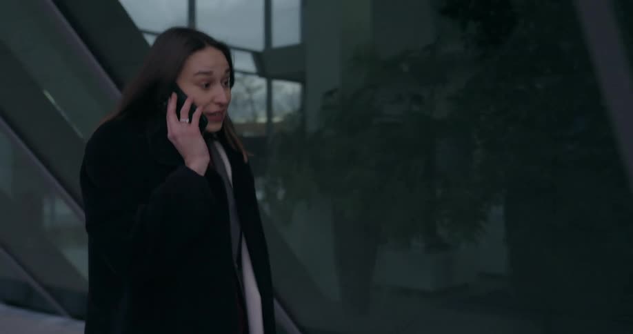 A woman is walking in a city and talking on a cell phone