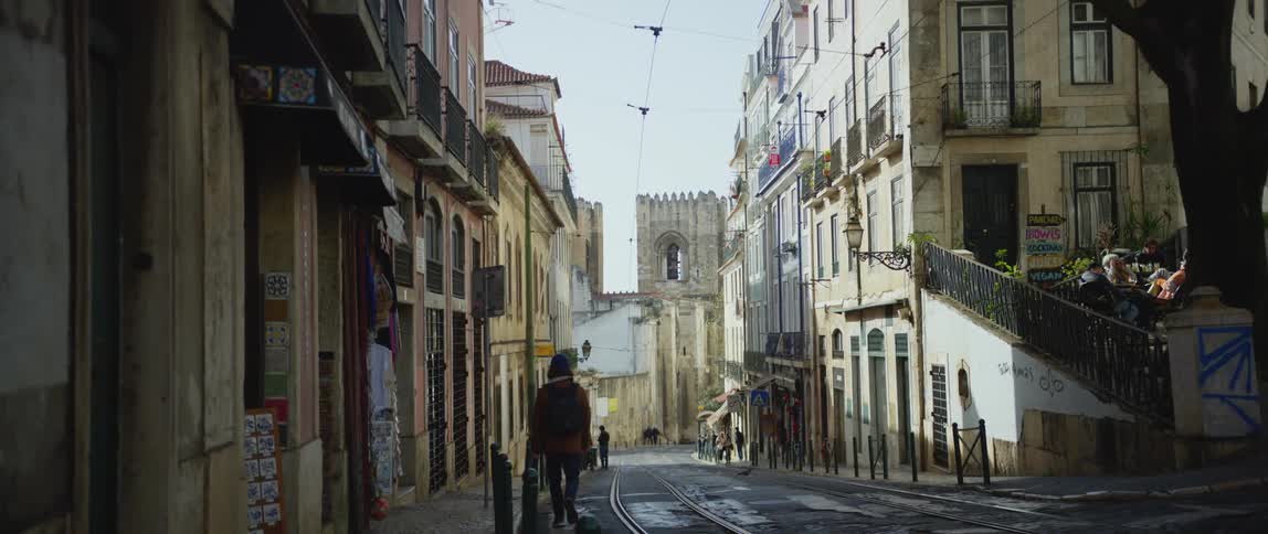 A pedestrian and car traveling on a small town road in the daytime