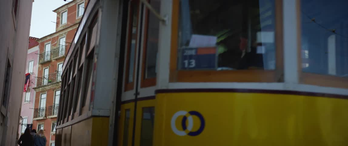 A public street car travels down a narrow road in a city during the day