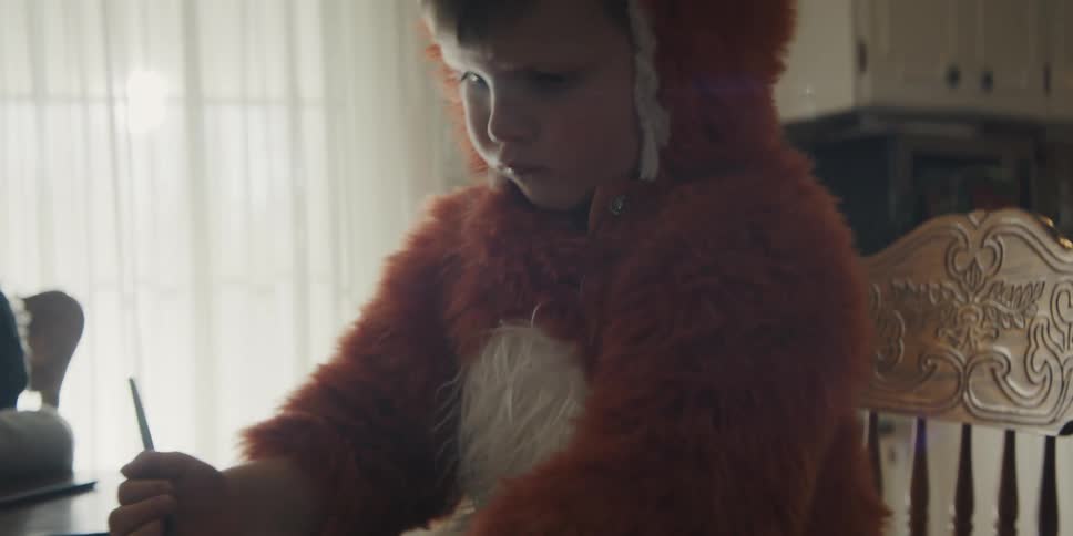 Children wearing animal costumes sit at dining table coloring in books