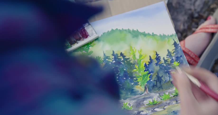 A person is sitting outdoors and painting a picture