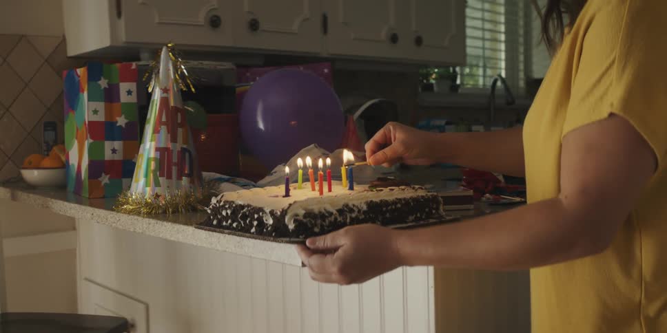Woman lighting birthday candles on a birthday cake