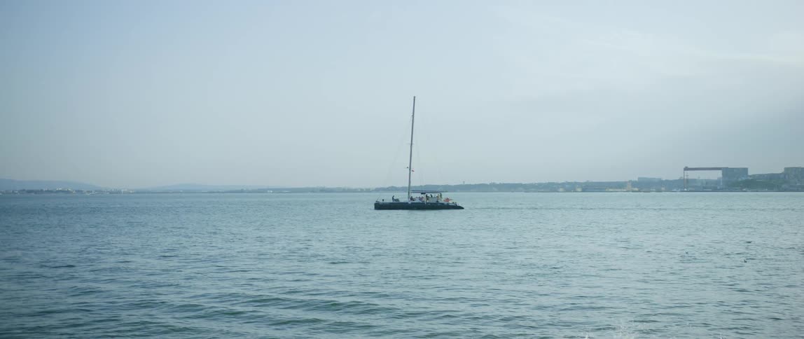 A boast with people on it sails in the ocean