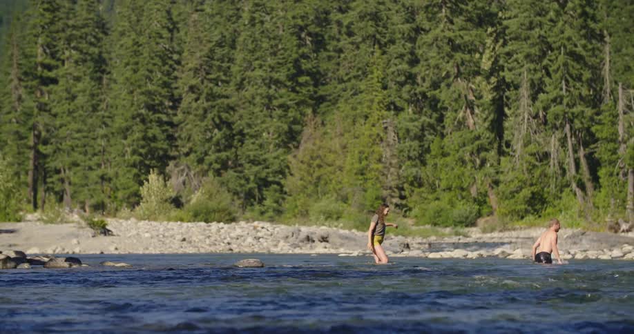 Three teenagers swimming in a riverbed in the wilderness