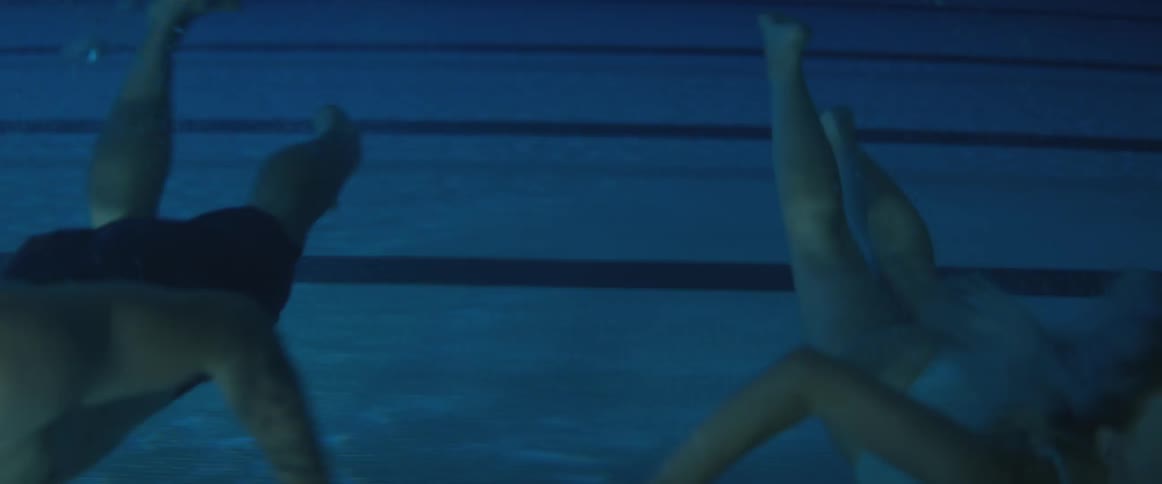 Man and woman swimming side-by-side underwater in a pool