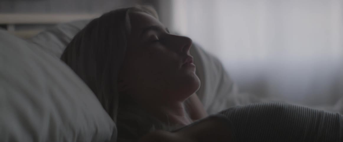 A blonde woman lies in bed