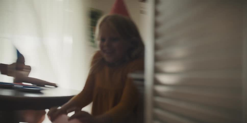 Little girl holding balloon being chased by a boy indoors at a birthday party