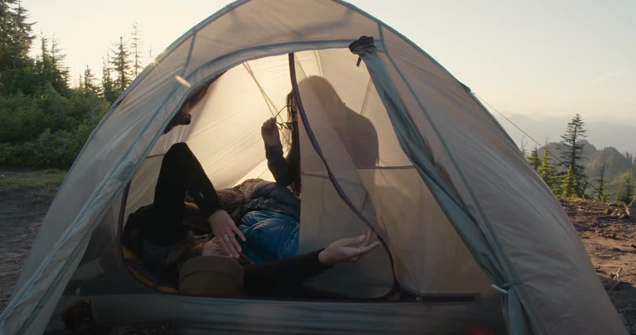 Friends are setting up a tent together in the wilderness