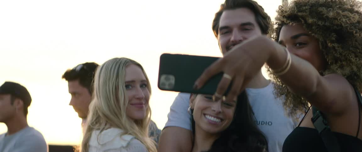 Group of friends standing together and talking a selfie on a smartphone with the view of a big city behind them