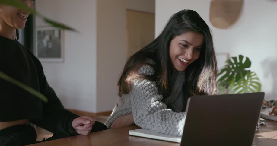 Two women are working on something on a laptop