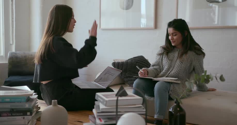 Two women are sitting in an office and working on something together